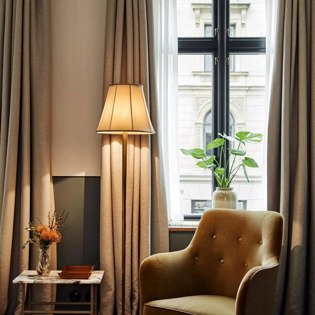 An armchair by a tall window in a Hotel Sanders room